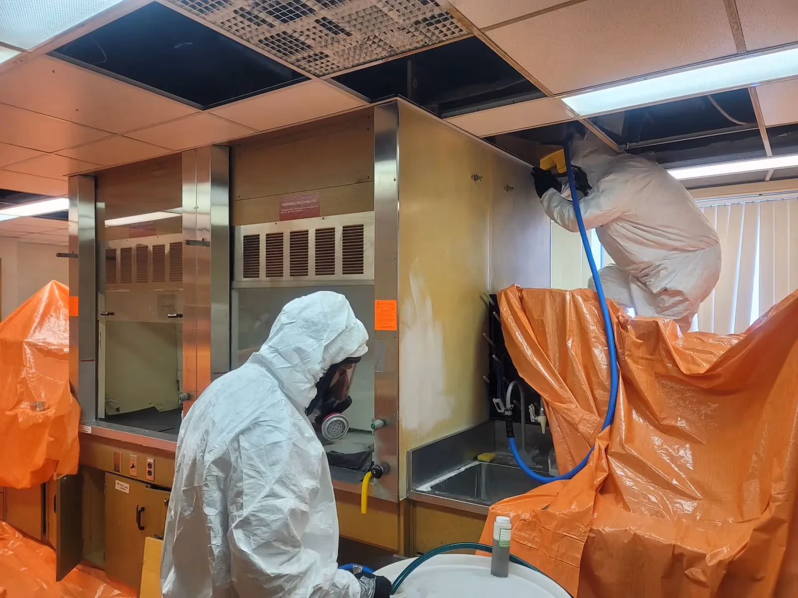 Technicians carrying out a controlled laboratory fume hood washdown